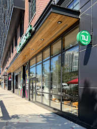 A storefront with a green sign that has the letters "TL" on it.