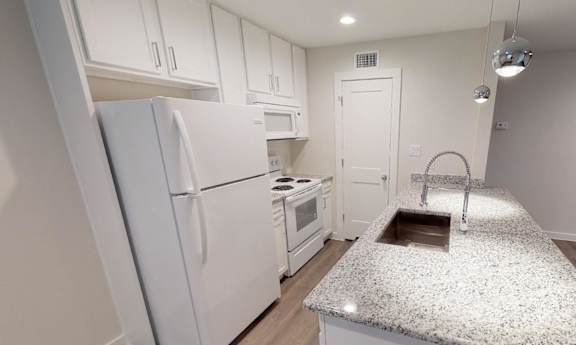 Kitchen with white cabinets, granite countertop and large center island.
