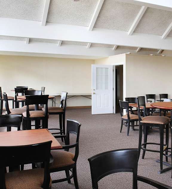 A room with a white door and chairs and tables.
