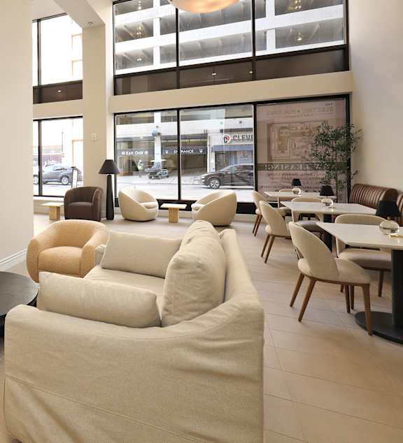 A white couch with a white chair in front of a window.