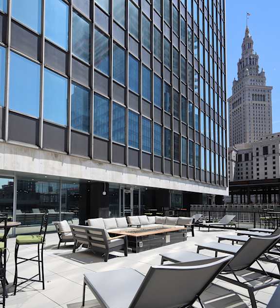 A large glass building with a lot of windows and a balcony with chairs and tables.