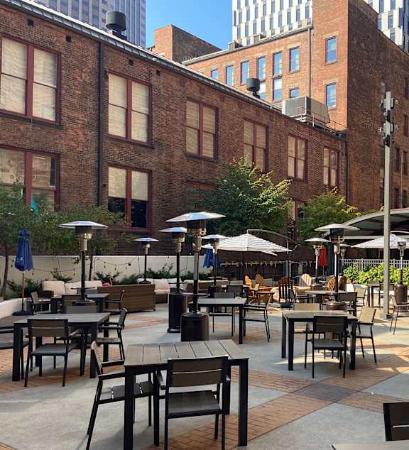 A patio with tables and chairs and umbrellas.