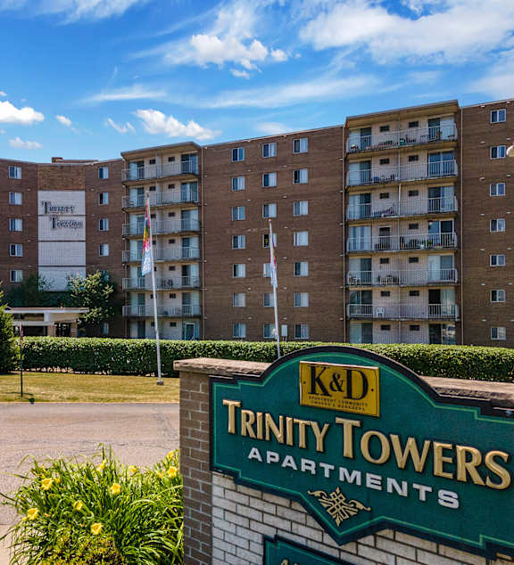 A sign for Trinity Towers Apartments in front of a building.