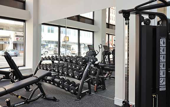 A gym with a row of dumbbells and a weight machine.