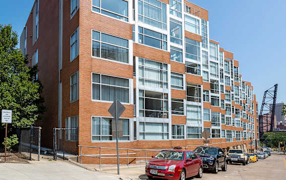 A red car is parked in front of a building with a yellow crosswalk.