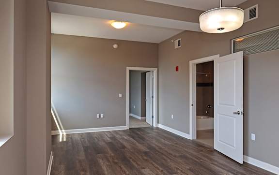 A room with wood flooring and a light hanging from the ceiling.
