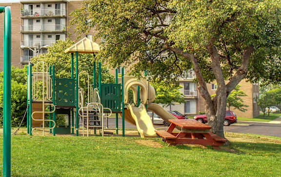 A playground with a yellow slide and a red picnic table.