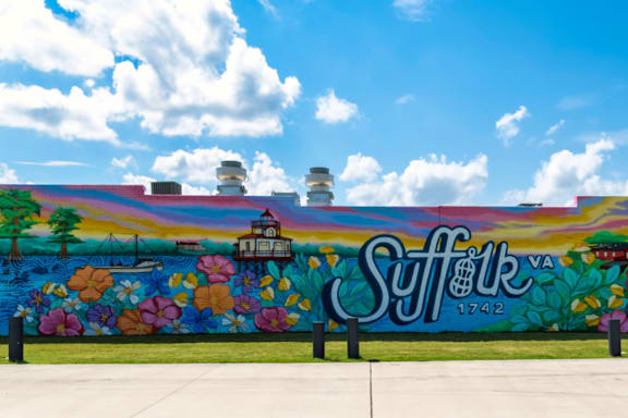 A wall with a mural of a cityscape and the word "Suffolk" painted on it.