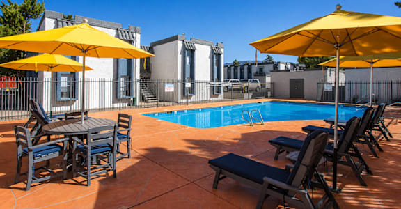 A pool area with sun loungers and umbrellas.