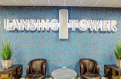 Two brown leather chairs are placed in front of a blue wall with the word "LANSING TOWER" written on it.
