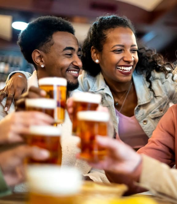 a group of people sitting at a table laughing and drinking beer
