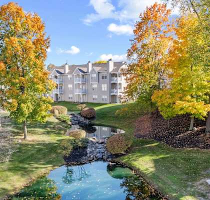 a park with a pond and trees in front of a building