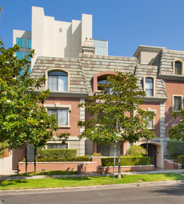 Street view of apartment building with trees and grass