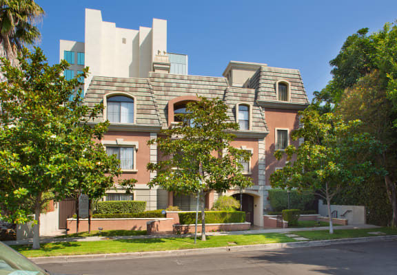 Street view of apartment building with trees and grass