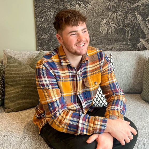 a man in a plaid shirt sitting on a couch