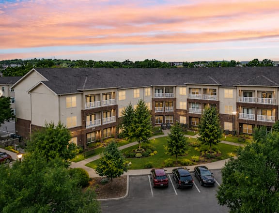 A large apartment complex with a parking lot in front.