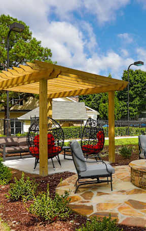 A patio with a fire pit and chairs.