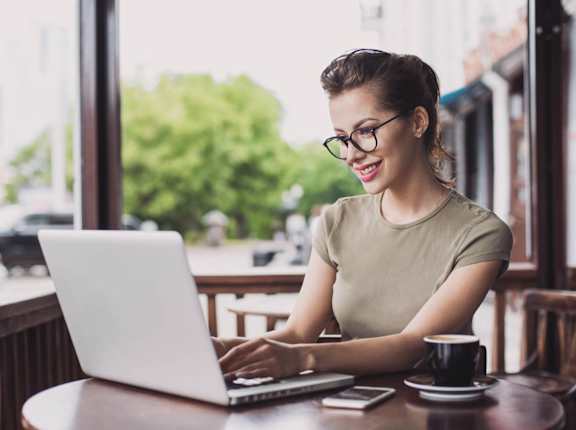 a woman sitting at a table using a laptop computer