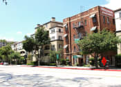 Thumbnail 28 of 29 - Street view of Brookmore apts in Pasadena CA. Four story brick building with "now leasing" sign and large green trees and bushes in front