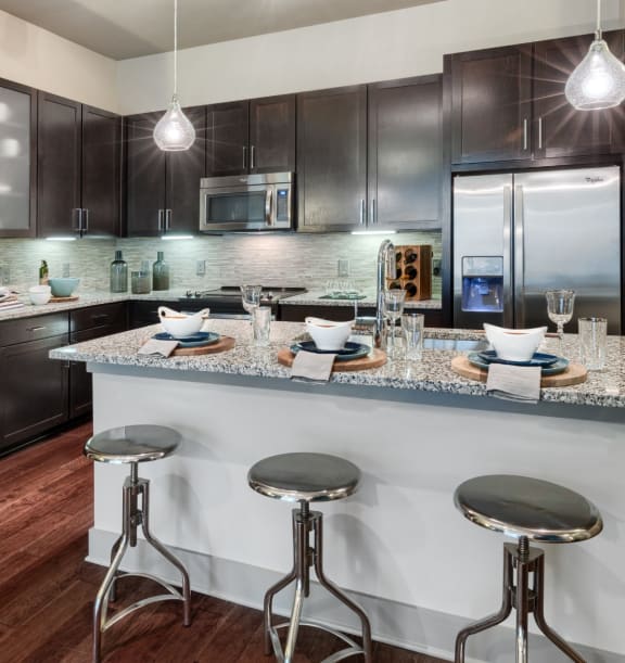 a kitchen with dark cabinets and a large island with a breakfast bar
