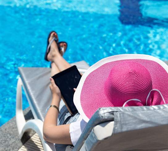 A woman in a pink hat is lounging by the pool.