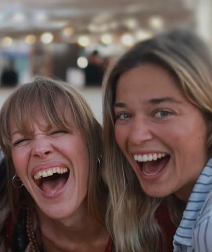 Four women are laughing together in a close group.