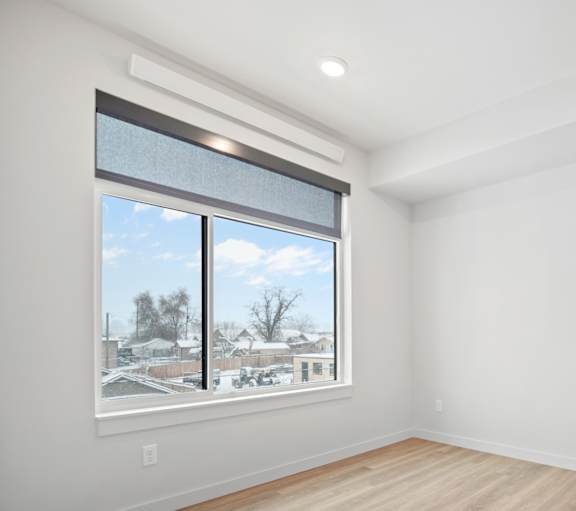 an empty living room with a large window and wood floors