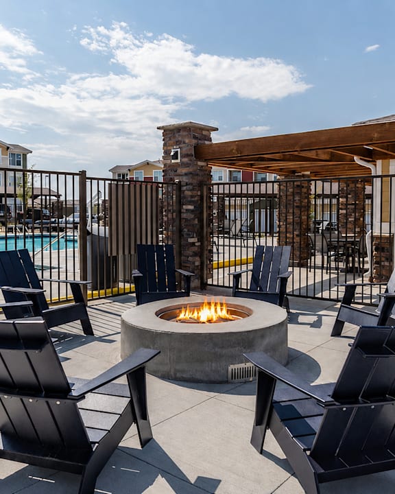 A patio with a fire pit and chairs.