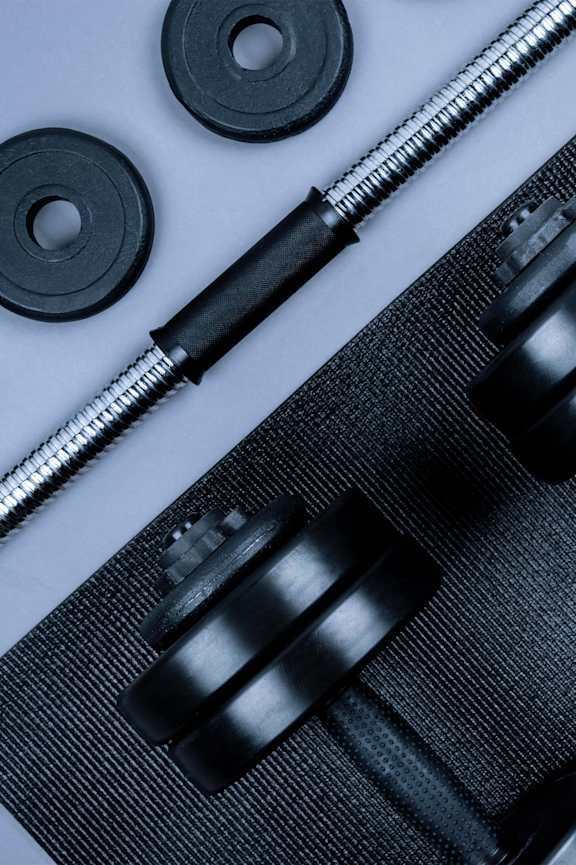 A set of dumbbells and a barbell on a mat