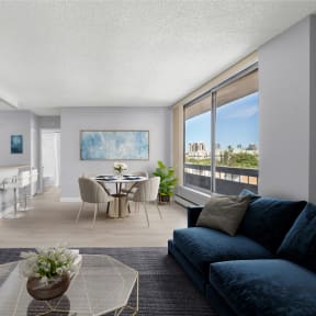 an open living room with a blue couch and a table with chairs and a kitchen