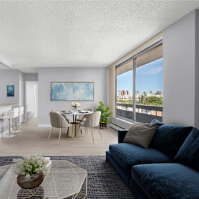 an open living room with a blue couch and a table with chairs and a kitchen