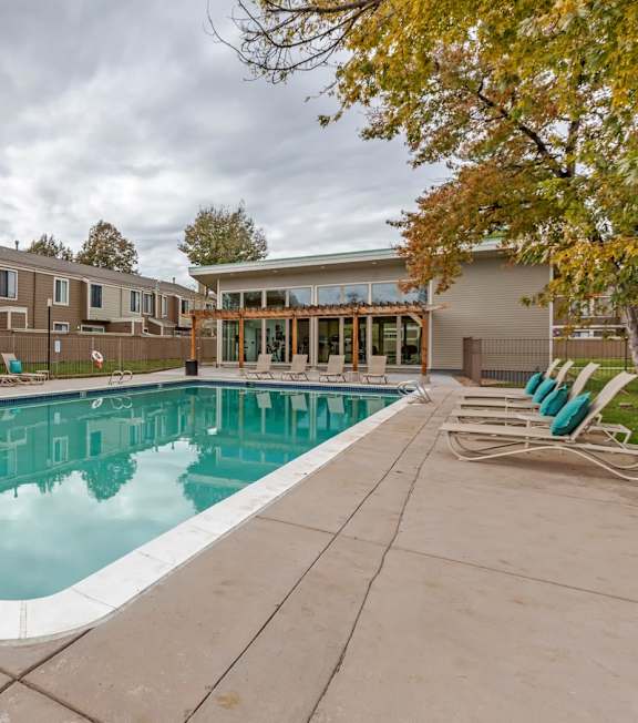 A swimming pool surrounded by a concrete floor and a wooden fence.