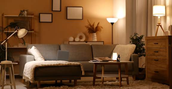 A cozy living room with a grey sofa, a wooden coffee table, and a lamp.