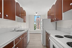 a kitchen with white appliances and wooden cabinets and a window