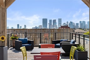 a rooftop deck with furniture and a city skyline in the background