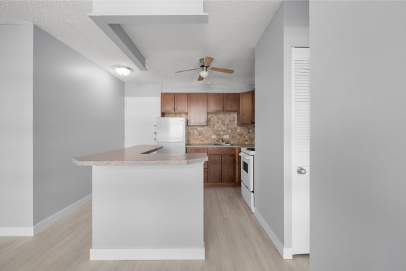 a renovated kitchen with an island and a ceiling fan