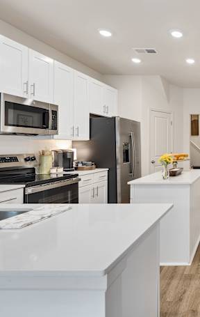 A modern kitchen with a long wooden table in the middle of the room.