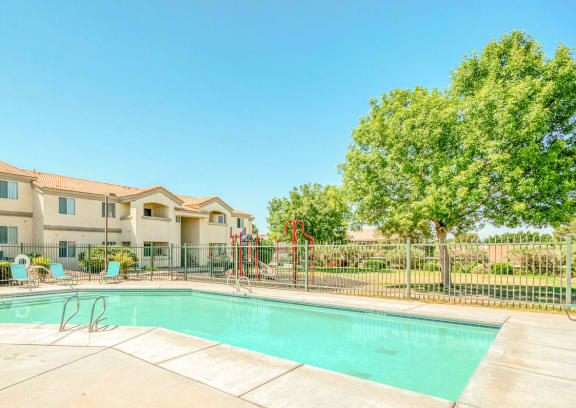 a swimming pool with a fence and apartment buildings in the background