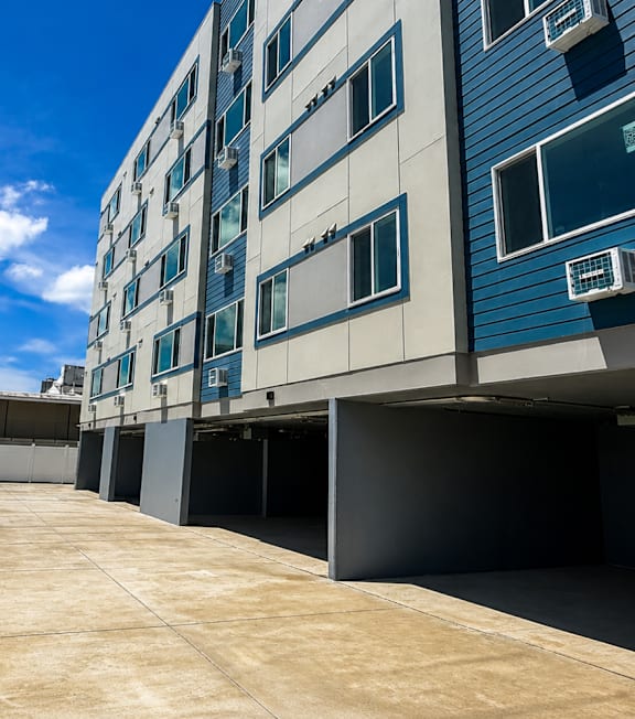 A long concrete walkway leads to a modern building with blue and white exterior.