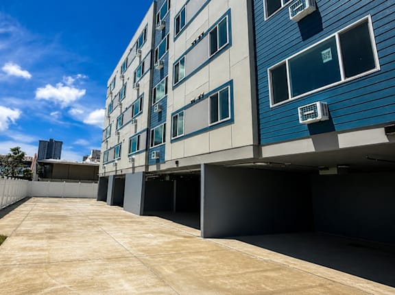 A long concrete walkway leads to a modern building with blue and white exterior.