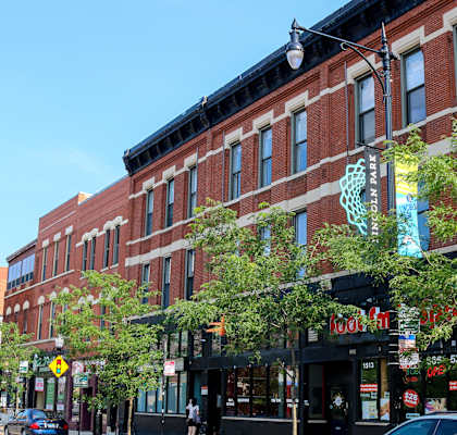 A street view of a city with a red brick building on the corner.