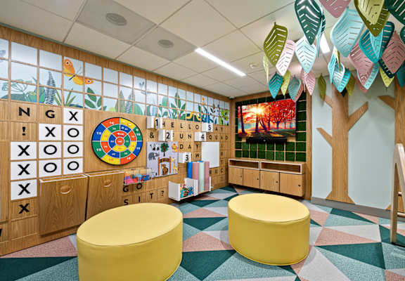 a mural of a tree and alphabet blocks decorates the wall of a classroom