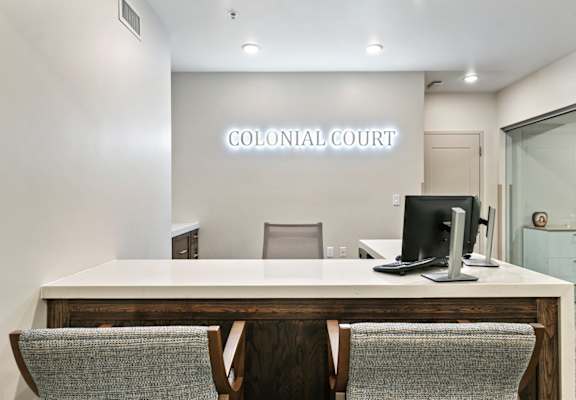 a large desk with chairs in front of it with the words colonial court on the wall