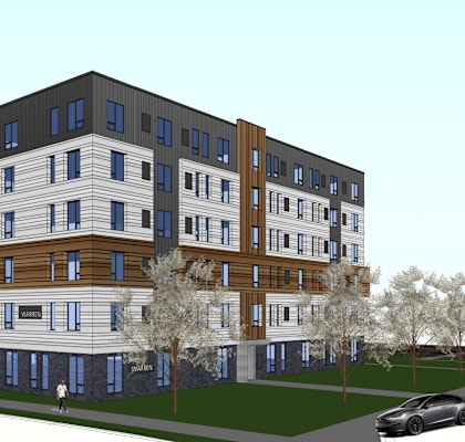 A modern multi-story apartment building with a car parked in front.