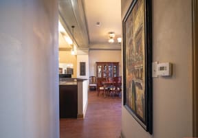 a hallway leading to a dining room and kitchen with a painting on the wall