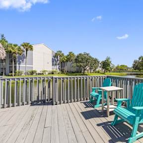 a deck with two blue chairs and a table on it