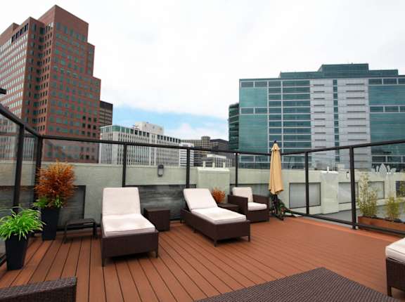 A wooden deck with two lounge chairs and a table at El Greco Lofts, Los Angeles, CA