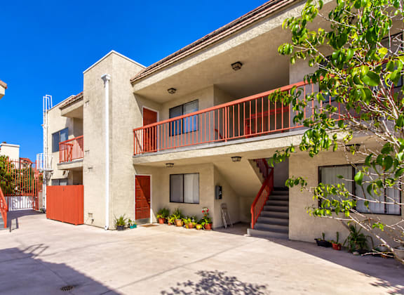 A building with a red railing and a tree in front.