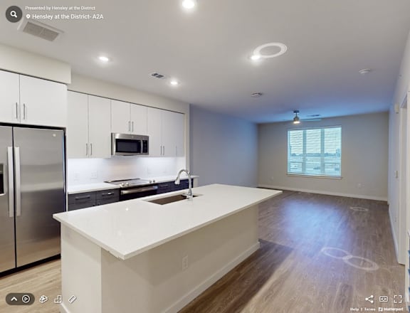 A modern kitchen with a white countertop and stainless steel appliances.