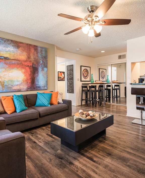 A living room with a brown couch and a painting on the wall.